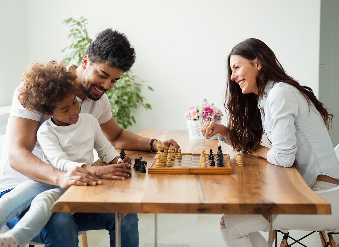 Personal Insurance - Happy Mother and Father Play Chess With Their Daughter at Home